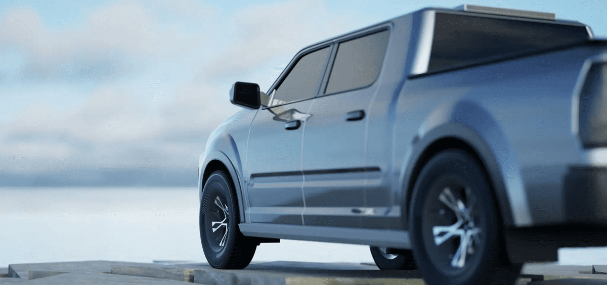 Silver pickup truck parked on a raised platform with a blurred scenic background.